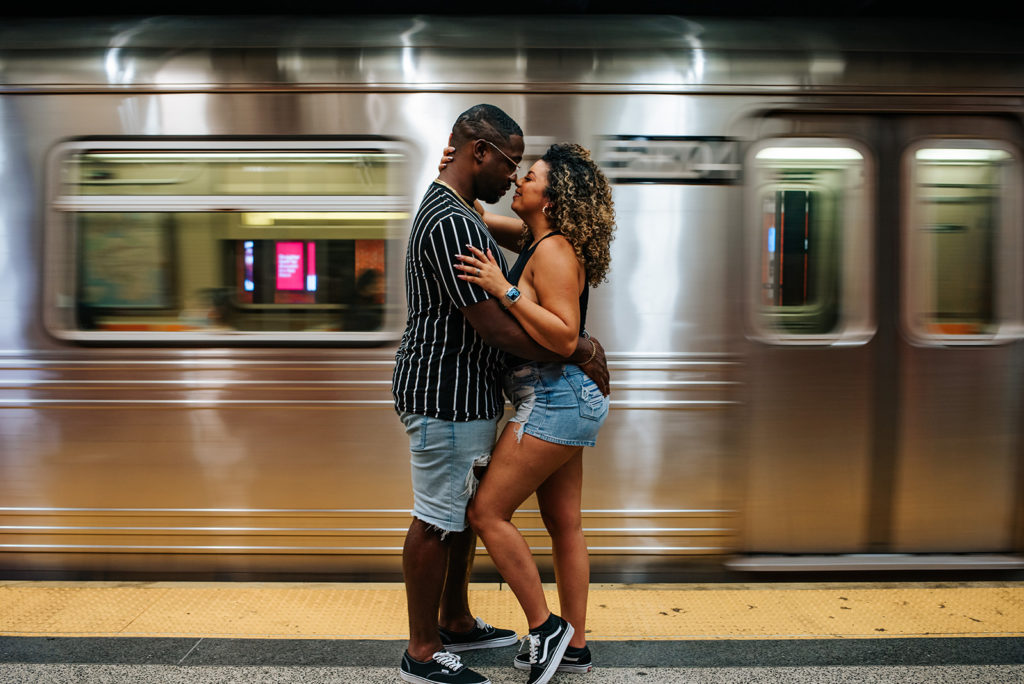 New York City couple in the subway during photoshoot with fast train in background