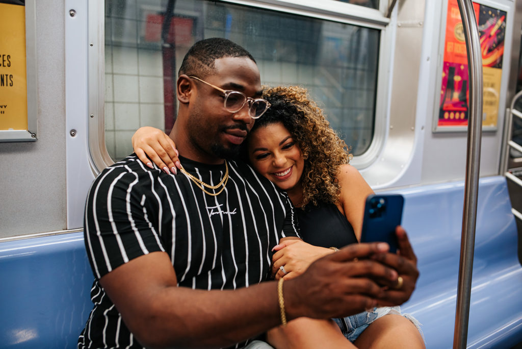 New York City couple taking a selfie in the subway during photoshoot
